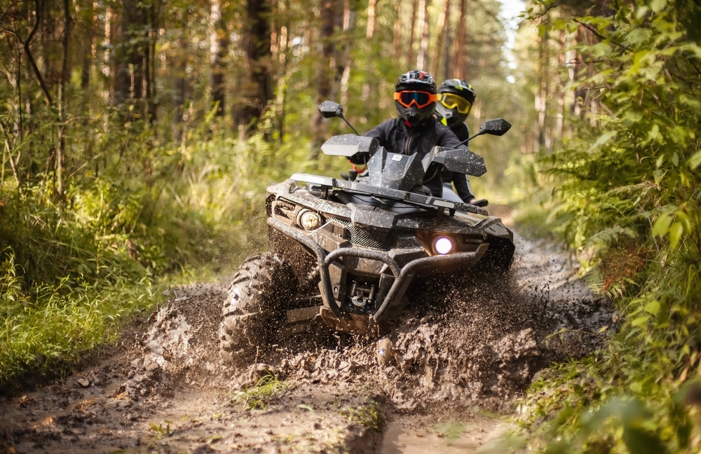 A,Quad,Moving,Trough,The,Mud,With,Two,Riders,On
